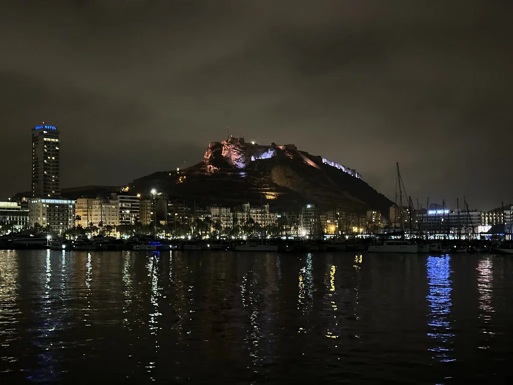 Alicante harbour at night with the floodlit Santa Bárbara Castle.