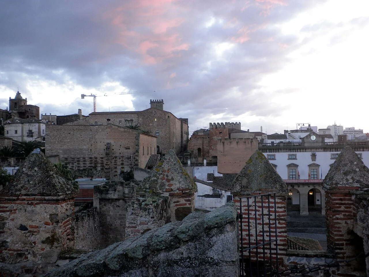 Rooftops and towers of Cáceres old town under a cloudy sky.