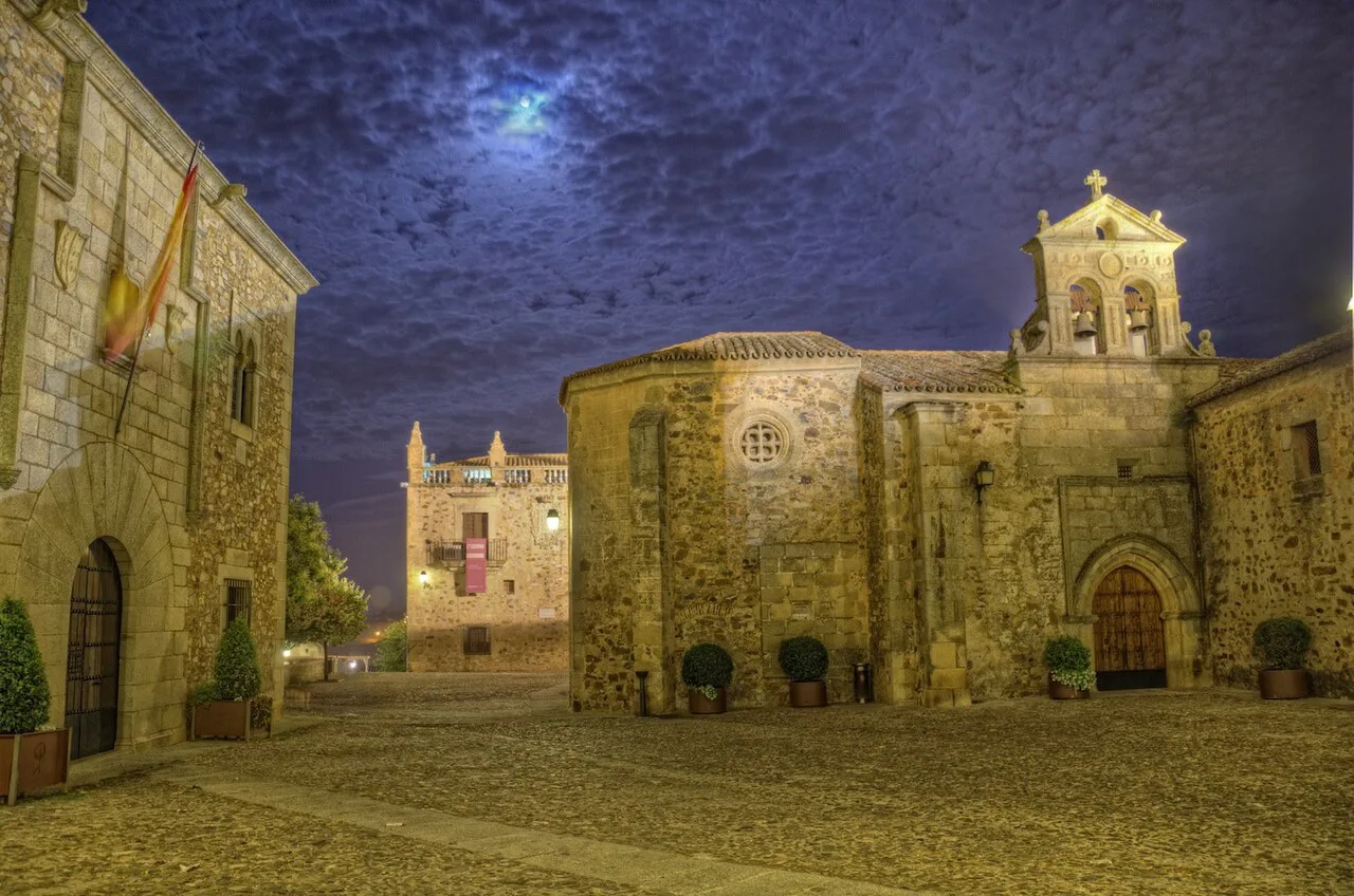 Floodlit square in Cáceres old town at night.