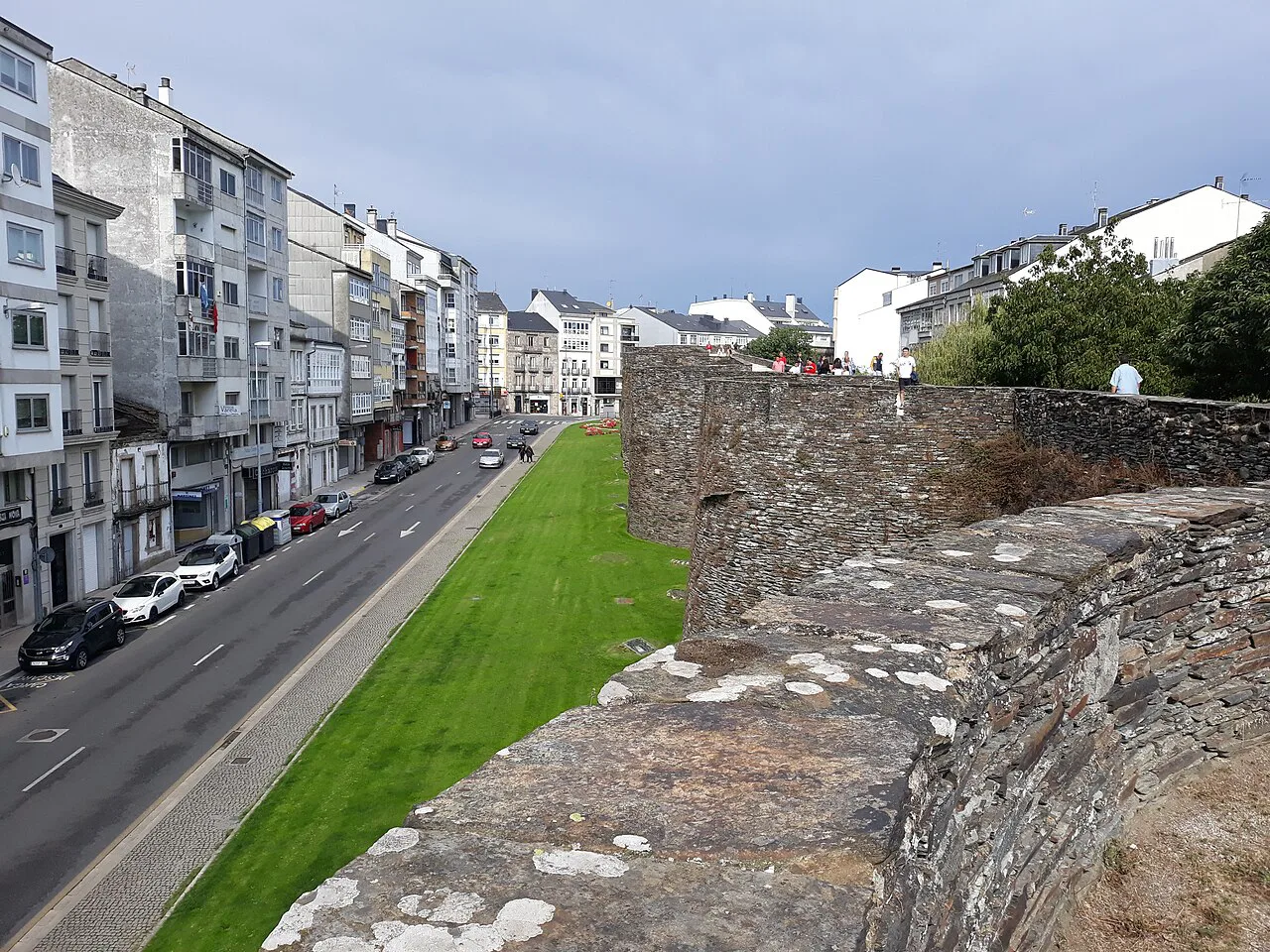 The Roman walls of Lugo beside a city street.