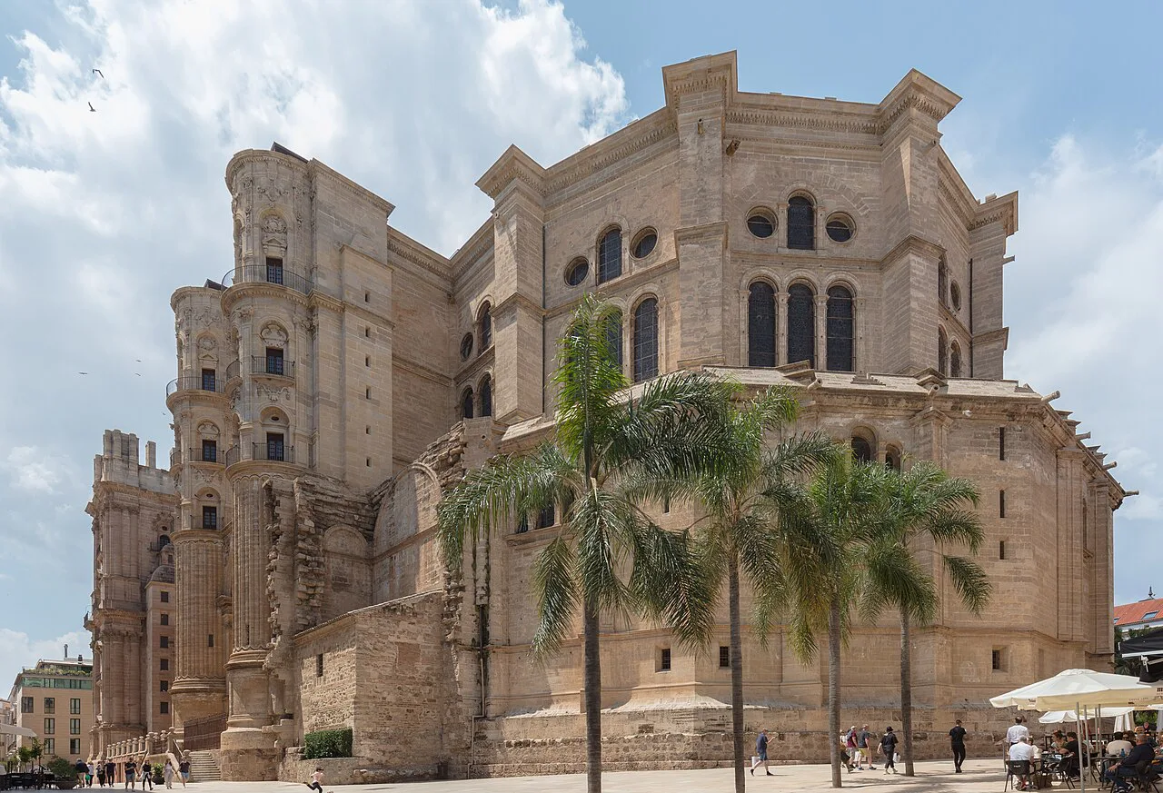 The exterior of Málaga Cathedral with palm trees.