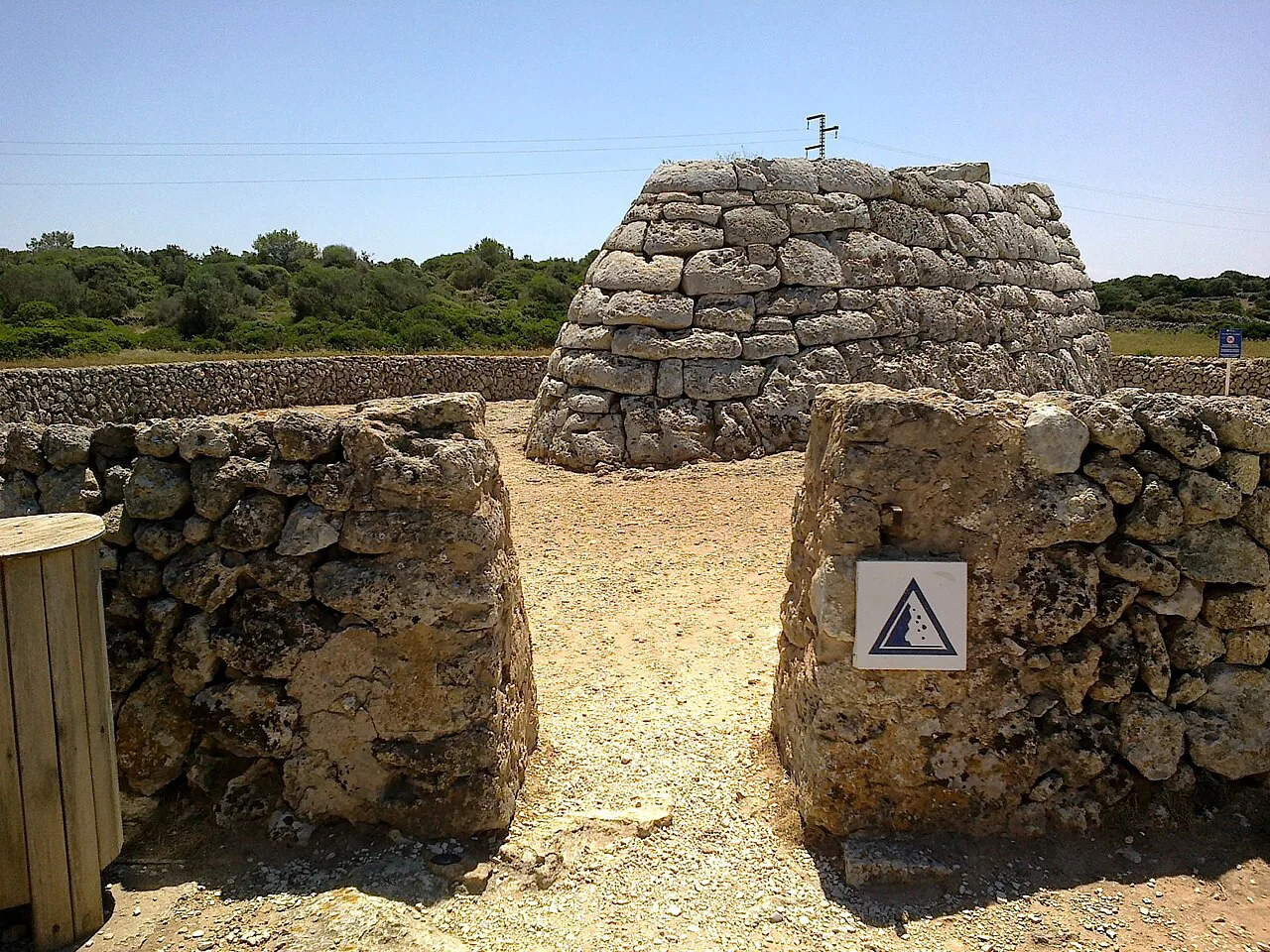 The Naveta des Tudons seen through its stone enclosure, Menorca.