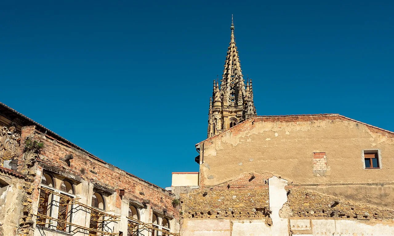 The Gothic tower of Oviedo Cathedral above old stone walls.