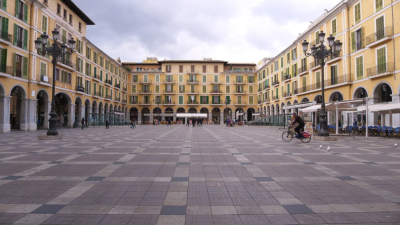 The arcaded Plaça Major in Palma de Mallorca under a cloudy sky.