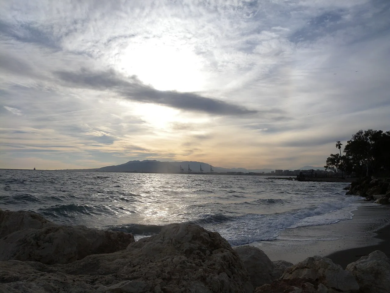 The rocky shore at Pedregalejo beach under a cloudy sky, Málaga.