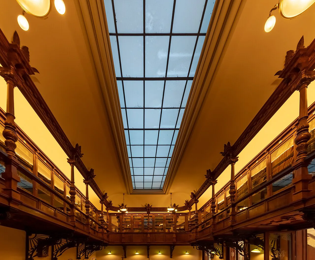 A skylit hall lined with bookcases in the Real Casino de Murcia.