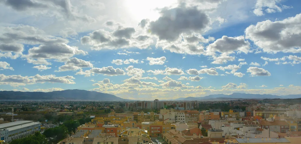 Murcia's rooftops and surrounding hills under an evening sky.