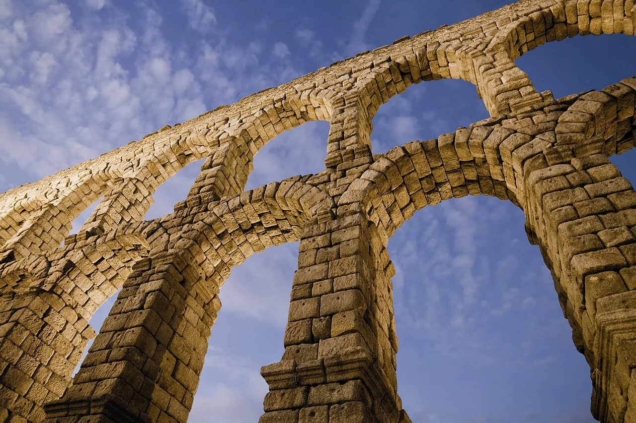 The stone arches of the Roman aqueduct of Segovia seen from below.