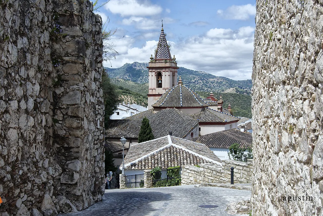The church tower of Zahara de la Sierra framed by stone walls.